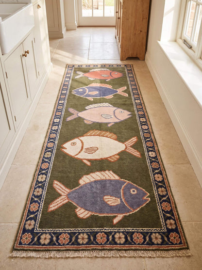 Hand knotted wool fish runner rug with coastal fish motifs and floral border in olive green and navy blue tones for beach house decor