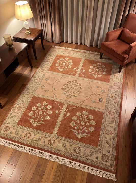 Hand knotted floral Oushak rug in rust and beige tones placed in a warm living room setting with wooden floor and accent chair __etsy:7970271821