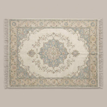 Persian style hand knotted rug featuring floral vines in blush, sage, and muted blue tones
