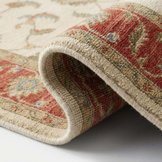 Close-up of hand knotted wool pile showing individual knots, natural fiber texture, and detailed floral weaving