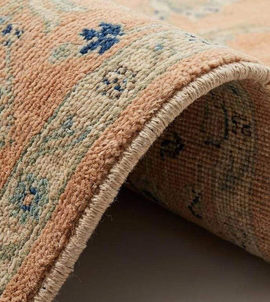 Close up detail showing hand-tied wool knots and soft pile texture of the apricot floral design.