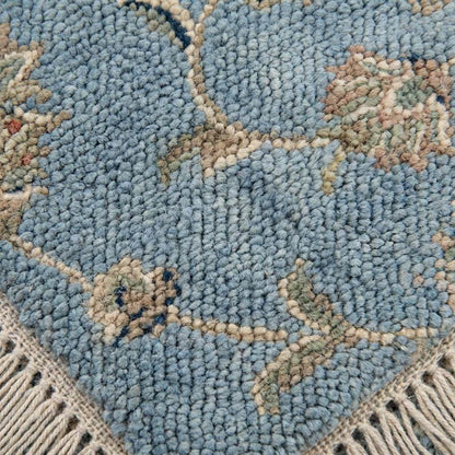 Close up detail of hand knotted wool pile texture showing individual knots and soft blue fibers.