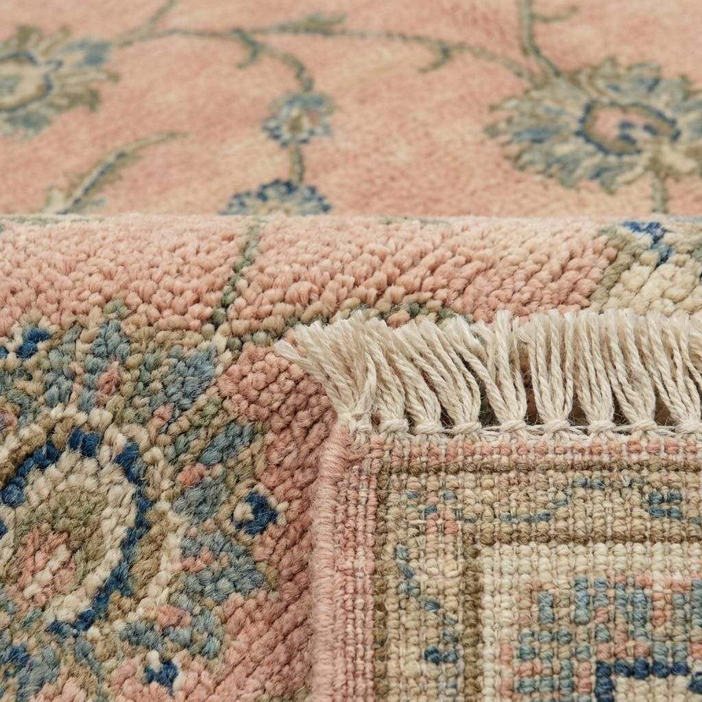 Close up of hand knotted wool pile showing individual knots and soft floral vine pattern.