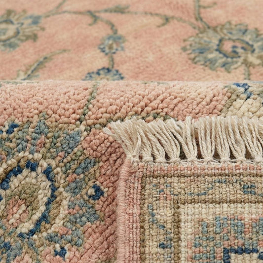 Close up of hand knotted wool pile showing individual knots and soft floral vine pattern.