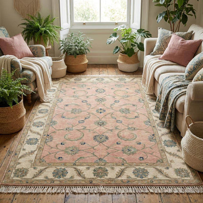 Soft pink Oushak area rug styled in a bright room next to a velvet armchair.