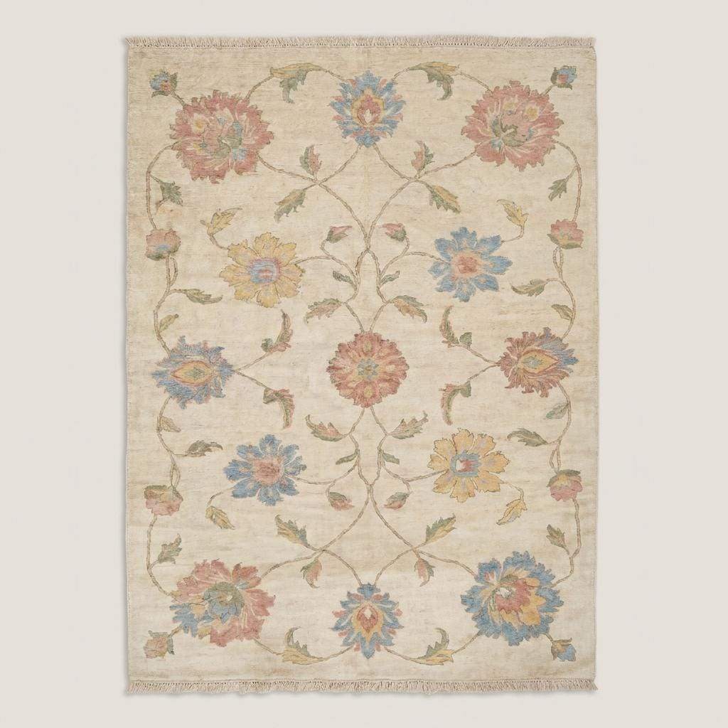 Large handmade floral area rug in ivory and pastel tones placed beside blush accent chair on wood floor __etsy:7950283506