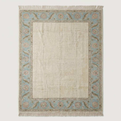 Neutral ivory and blue handmade wool area rug styled under modern accent chair near arched window