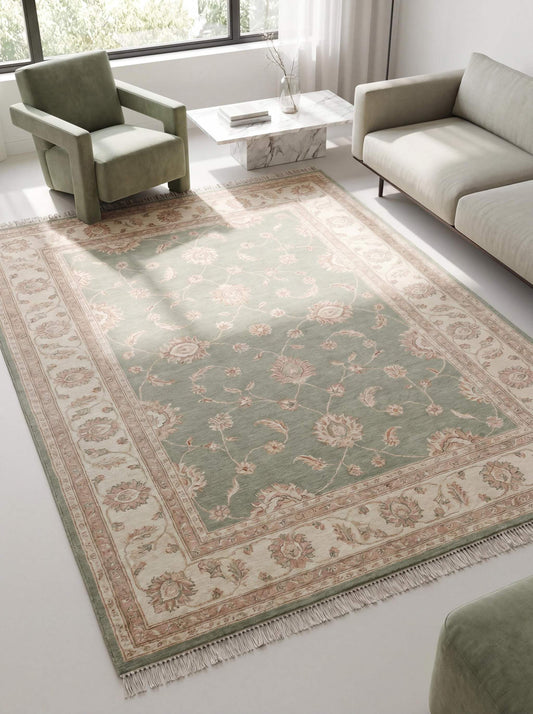 Hand knotted Oushak rug in sage green with ivory floral border placed in modern living room with sofa and chair __etsy:8005541483