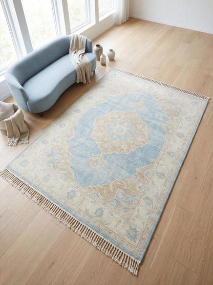 Hand knotted Oushak rug with blue wool medallion design in neutral living room setting