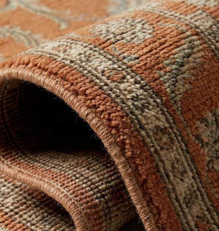 Close-up texture of a hand-knotted wool rug showing individual knot structure, low pile height, and intricate cream and olive green floral weaving.