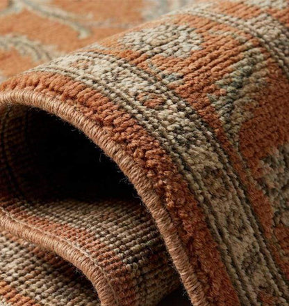 Close-up texture of a hand-knotted wool rug showing individual knot structure, low pile height, and intricate cream and olive green floral weaving.