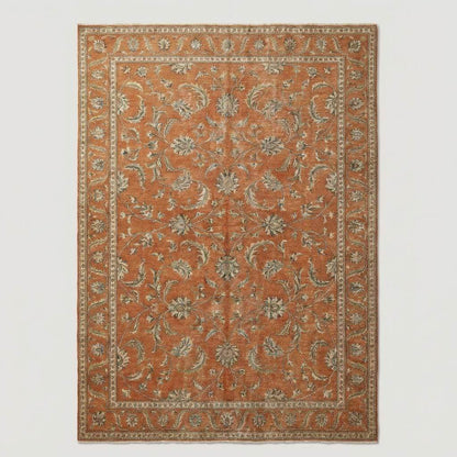 Overhead view of a large rust-colored area rug featuring a traditional floral border and a distressed, vintage-inspired transitional aesthetic.
