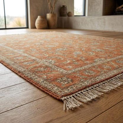 Detail of the hand-finished fringe and edge of a terracotta hand-knotted rug, highlighting the authentic craftsmanship and lack of synthetic backing.