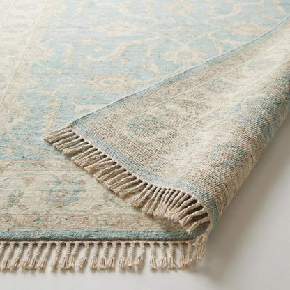 Hand knotted Oushak wool rug with vintage blue floral design in a soft neutral living room setting