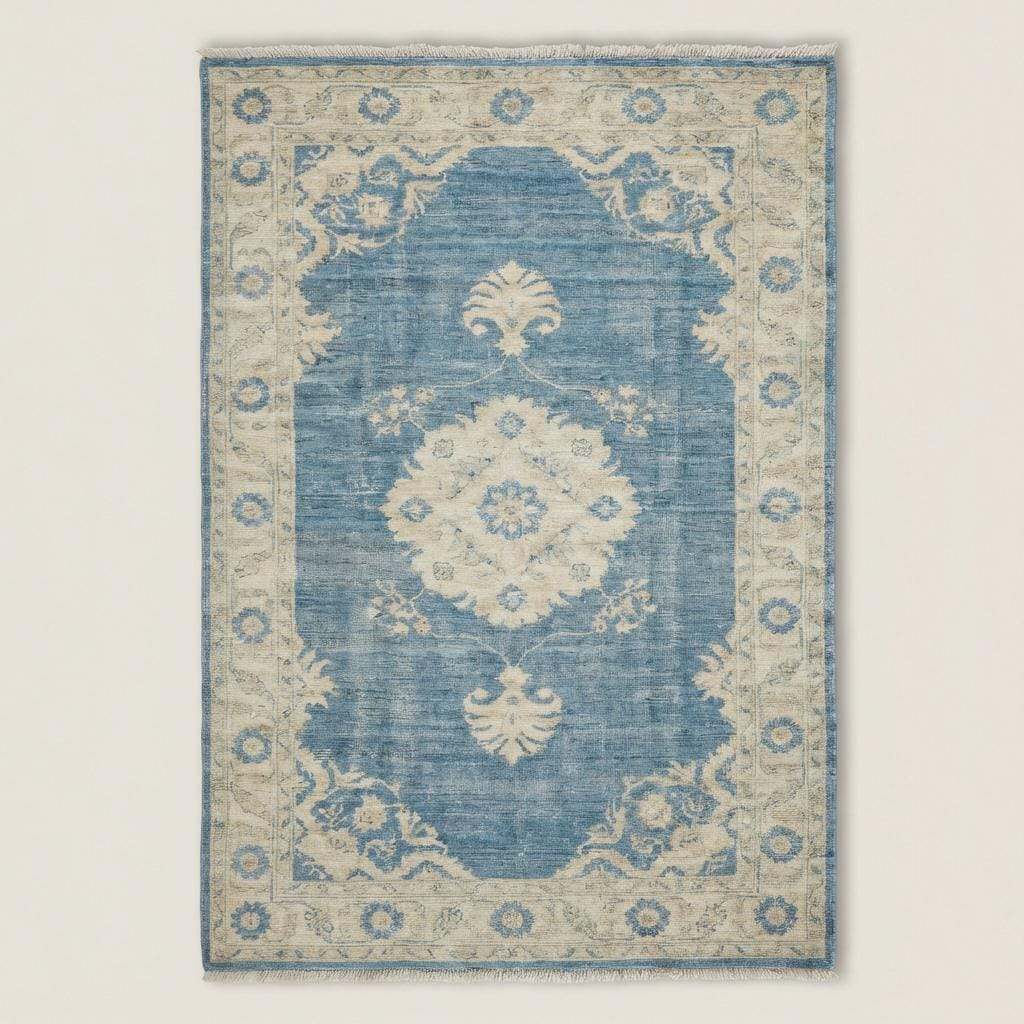 Rectangular blue medallion area rug with traditional Turkish Oushak pattern on light wood floor beside sofa