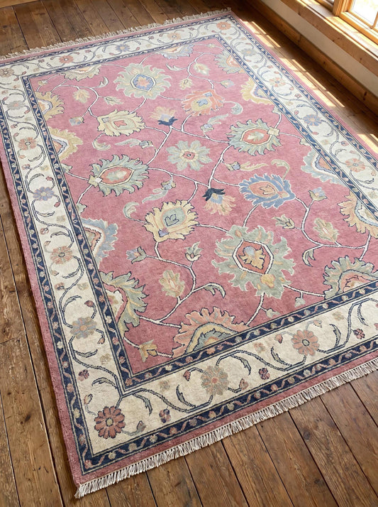 Hand knotted pink Oushak rug featuring traditional floral motifs and ivory border displayed on hardwood flooring. __etsy:8073700742