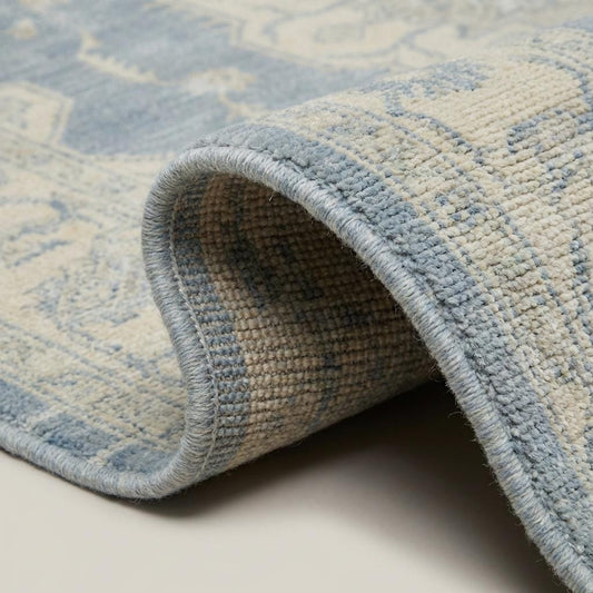 Close-up of dense hand knotted wool pile showing individual knots, soft vintage wash, and natural fiber texture