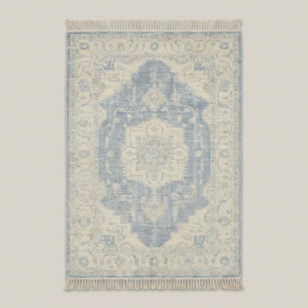 Traditional blue and ivory medallion hand knotted rug styled beside curved sofa and wooden floor