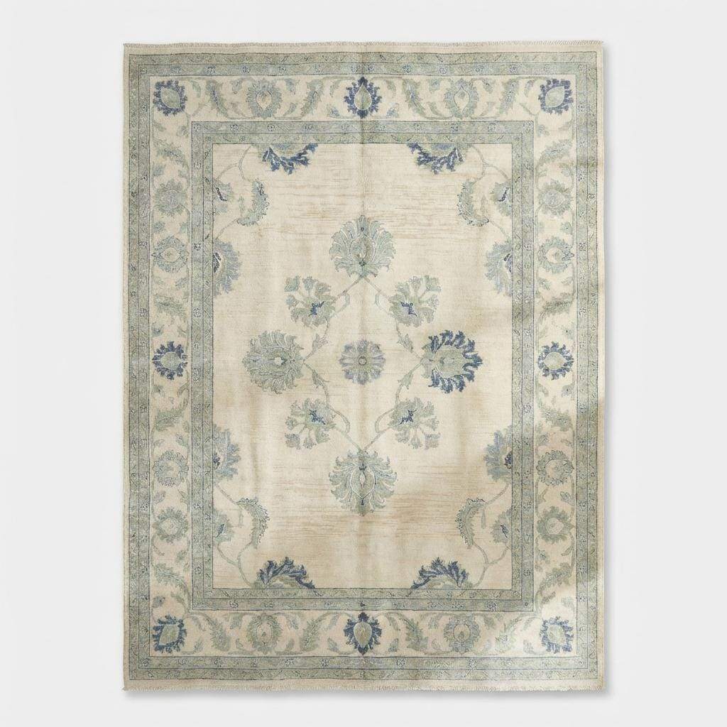 Detail of the large-scale transitional floral motifs and border pattern in soft slate blues and sage greens.
