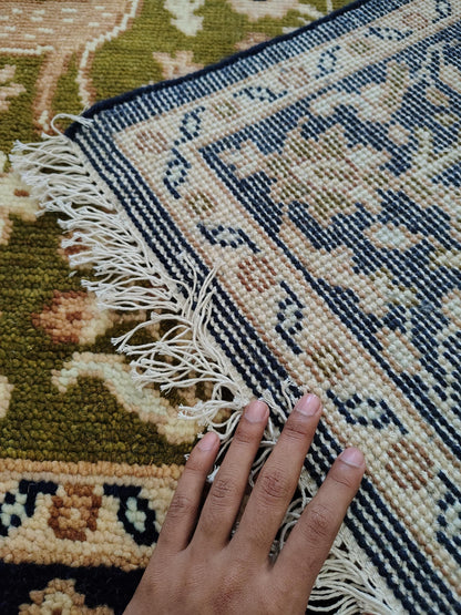 Hand knotted wool rug with green Persian animal motif and navy floral border