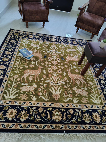 Hand knotted wool rug with Persian animal motifs, green field and navy floral border