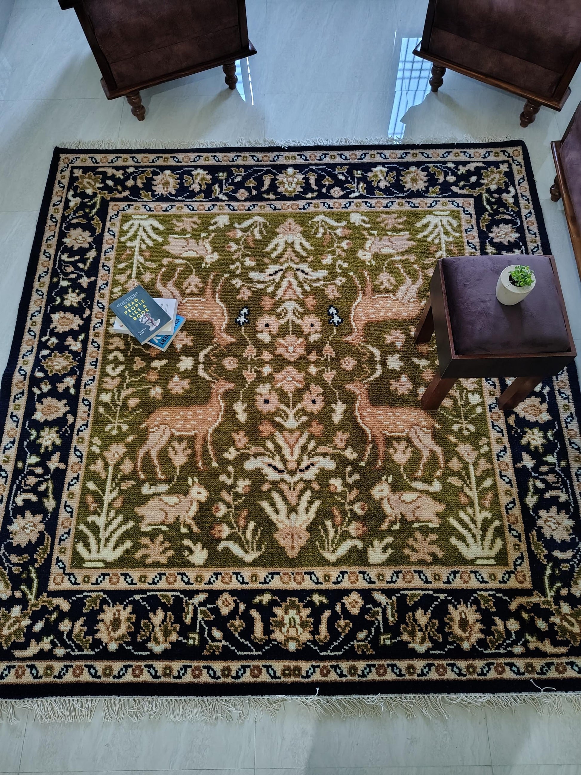 Hand knotted wool rug with green Persian animal motif and navy floral border
