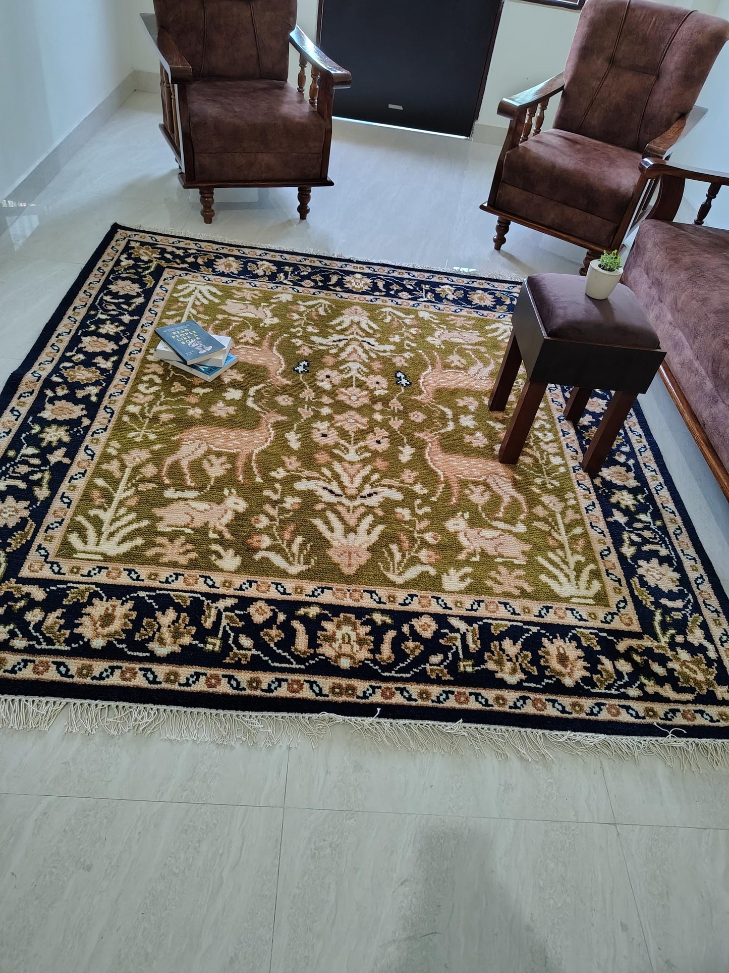 Hand knotted wool rug with green Persian animal motif and navy floral border