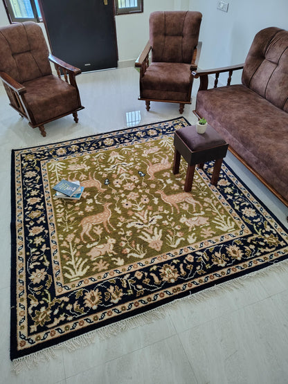 Hand knotted wool rug with Persian animal motifs, green field, navy floral border, traditional living room carpet