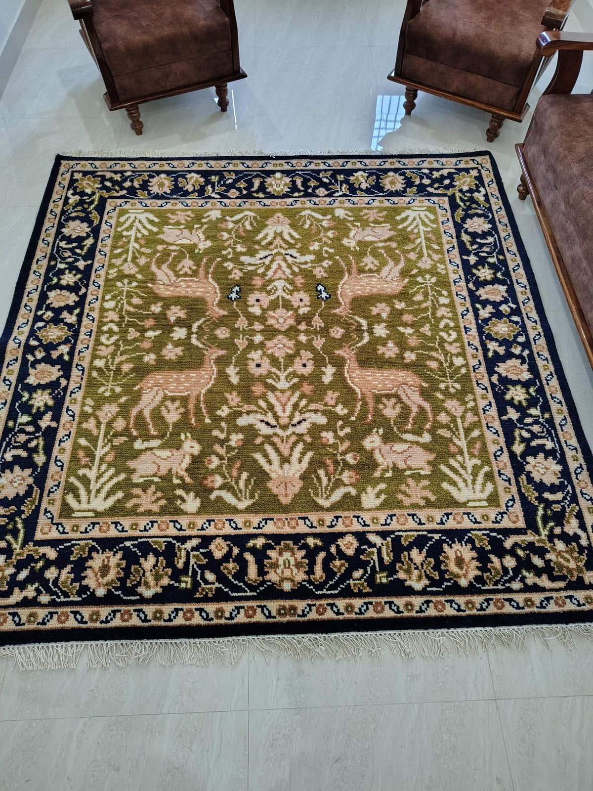 Hand knotted wool rug with green Persian animal design and navy floral border
