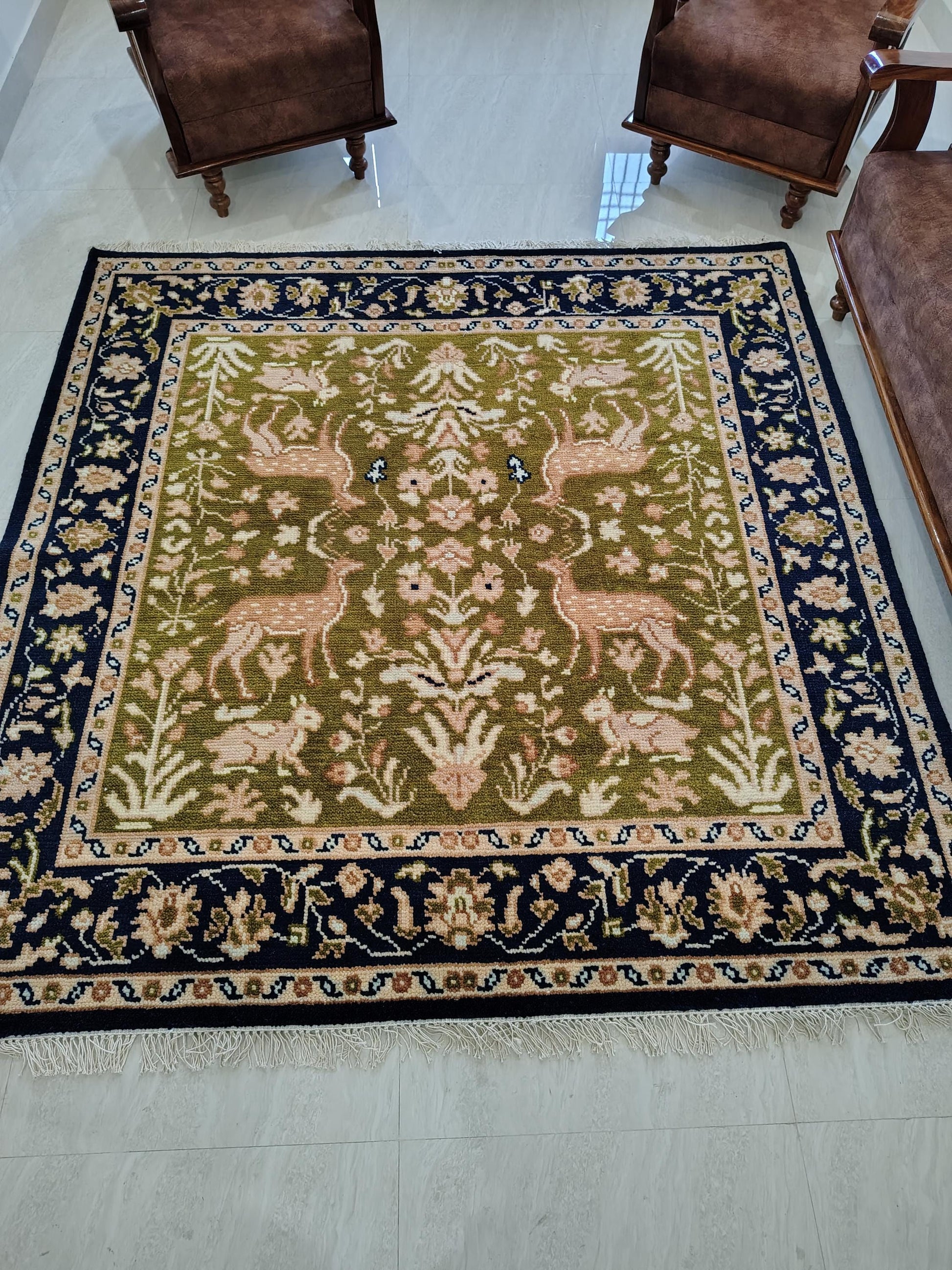 Hand knotted wool rug with green Persian animal design and navy floral border