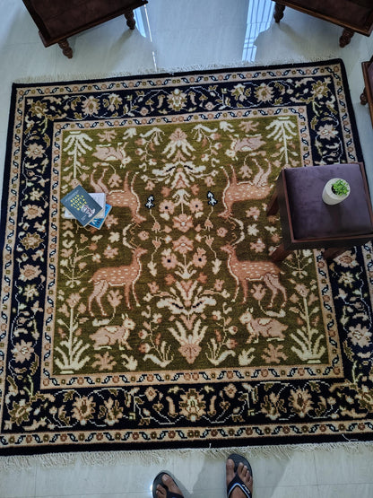 Hand knotted wool rug with green Persian animal motif and navy floral border