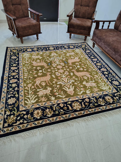 Hand knotted wool rug with green Persian animal motifs and navy floral border