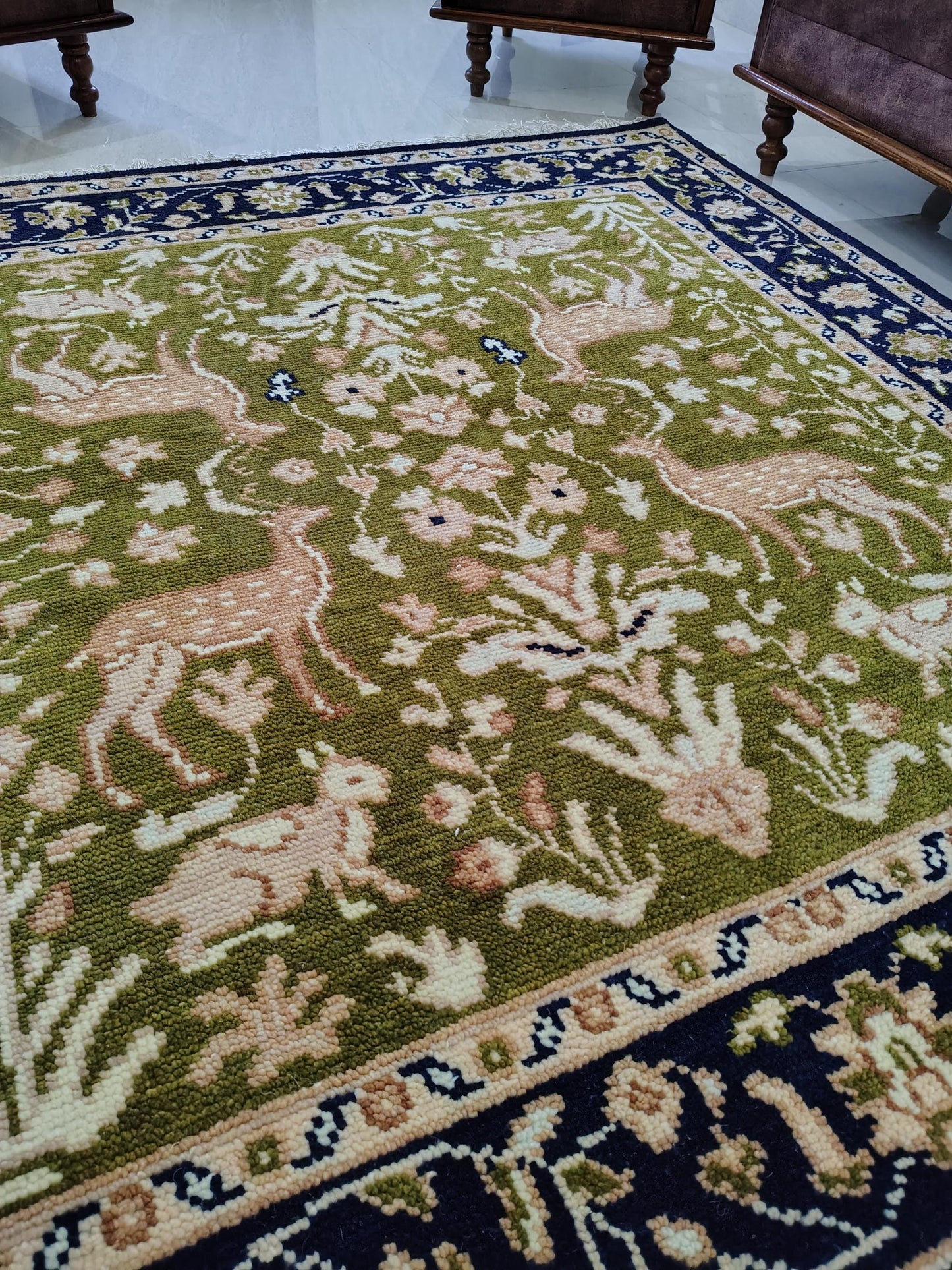 Hand knotted wool rug with green Persian animal motifs and navy floral border