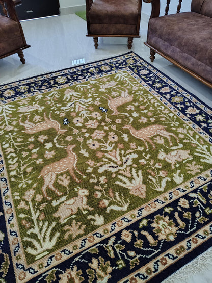 Hand knotted wool rug with green Persian animal motif and navy floral border