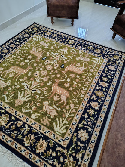 Hand knotted wool rug with green Persian animal motif and navy floral border