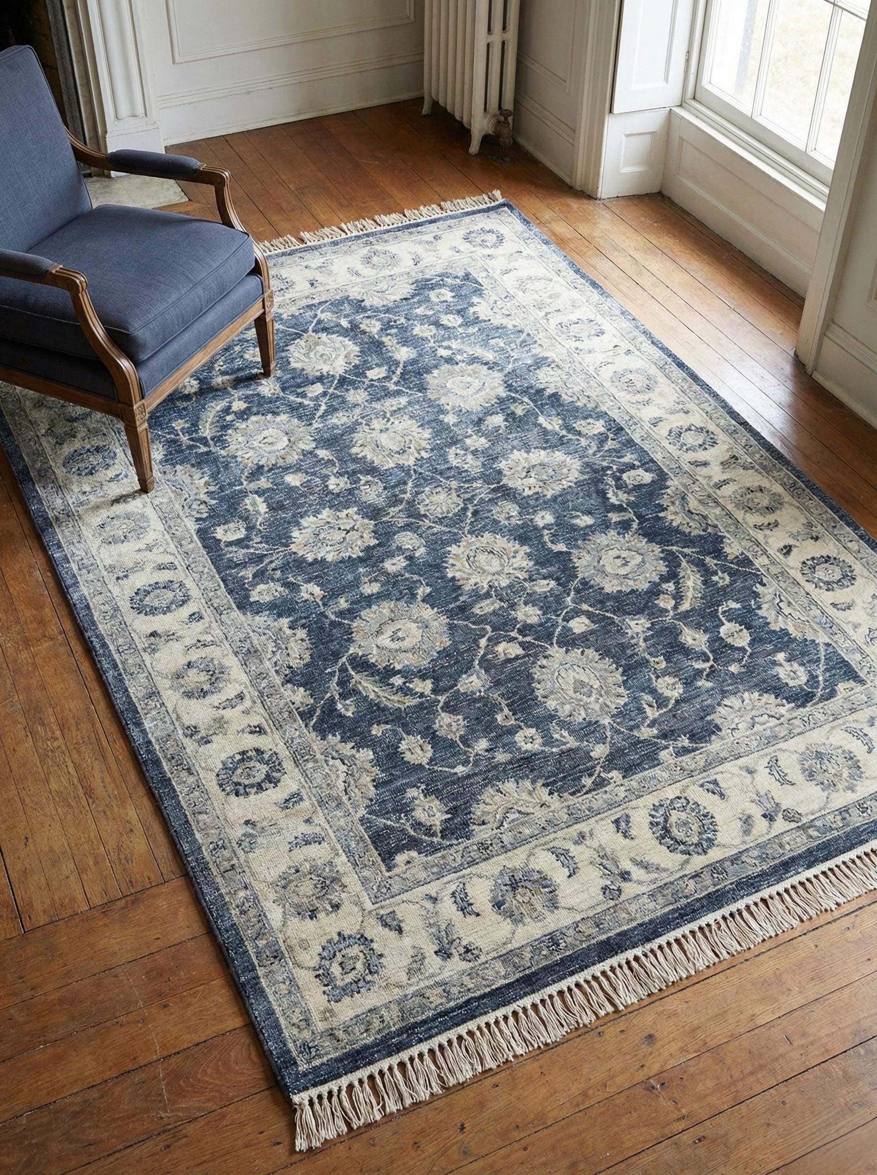Large hand-knotted wool rug in navy blue and ivory floral Oushak design, styled in a sunlit living room with hardwood floors and a blue armchair. __etsy:7636050400