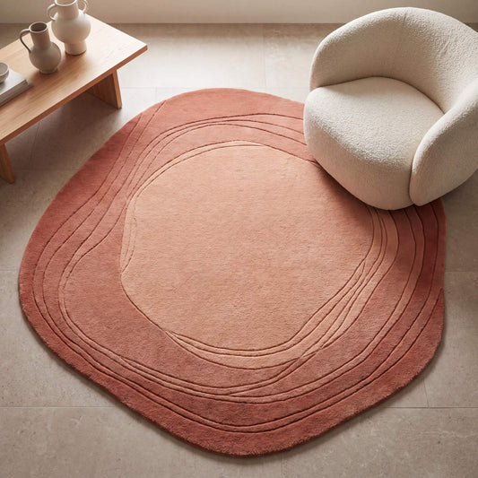 Hand tufted abstract wool rug in peach and terracotta tones placed in a modern minimalist living room with curved accent chair __etsy:8007287770