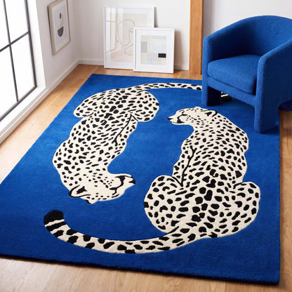 Hand tufted wool leopard rug featuring two spotted leopards on a royal blue background in a modern living room setting. __etsy:8131774051