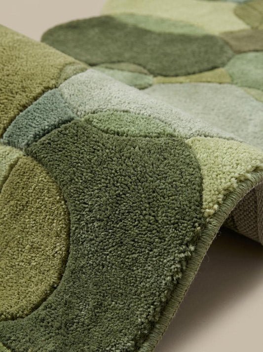 Close up of dense hand tufted wool pile showing soft cut pile texture and sculpted pebble shapes