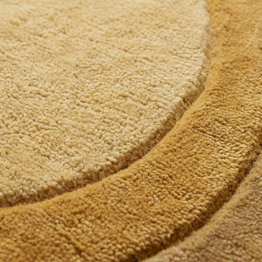 Close-up of dense wool pile on hand tufted rug showing soft plush texture, carved contour detailing, and matte natural fiber surface.