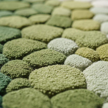 Hand-tufted pebble rug in green and teal with 3D textured stone design, soft and cozy for modern organic interiors