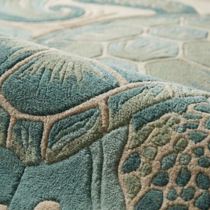 Close-up of hand tufted wool rug showing carved cut pile texture, sculpted sea turtle shell detailing, and raised wave patterns in teal and sand tones.