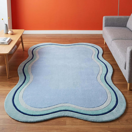 Hand tufted organic shape blue rug placed in a modern living room with soft curved wave border design __etsy:8036548444