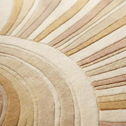 Close-up of dense hand-tufted wool pile showing carved sculpted channels and soft textured surface in cream and sand shades.