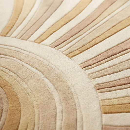 Close-up of dense hand-tufted wool pile showing carved sculpted channels and soft textured surface in cream and sand shades.