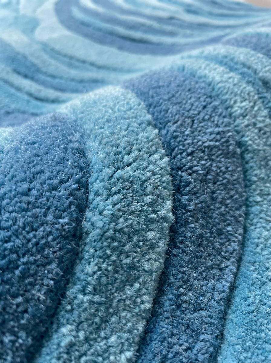 Close-up of hand tufted wool fibers showing soft cut pile texture, layered blue yarns, dense construction, and artisan craftsmanship. __etsy:8092948220