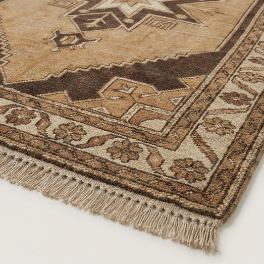 Close-up of hand knotted wool rug showing dense natural wool pile and individual knot texture with earthy beige and brown fibers.