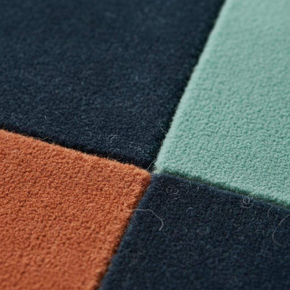 Handmade wool rug with modern retro geometric pattern in navy, terracotta, mint, and cream colors