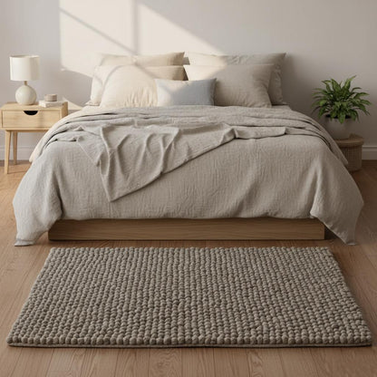 Close top view: rectangular wool felt-ball rug in stone taupe, handcrafted pom-pom texture, suitable as a gift or nursery accent rug.
