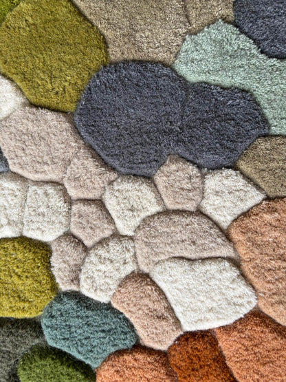 Handmade wool tufted moss rug with nature-inspired forest floor design in muted colors.